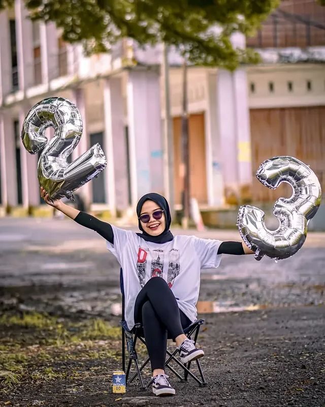 Sesi foto ulang tahun dengan kursi lipat dan balon angka di ruang terbuka